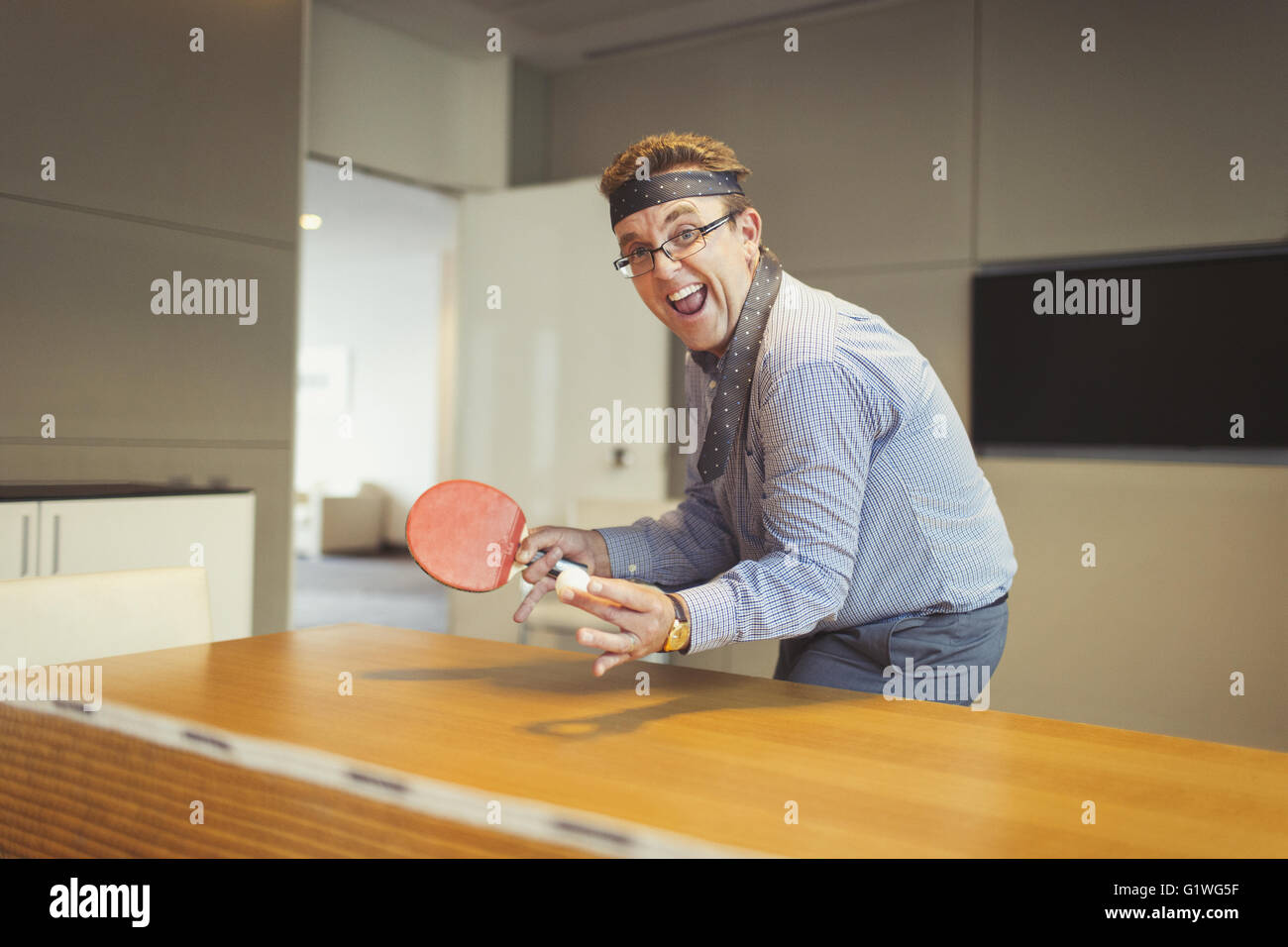 Ritratto di imprenditore entusiasta giocando a ping pong con cravatta avvolto attorno alla testa della sala conferenze Foto Stock