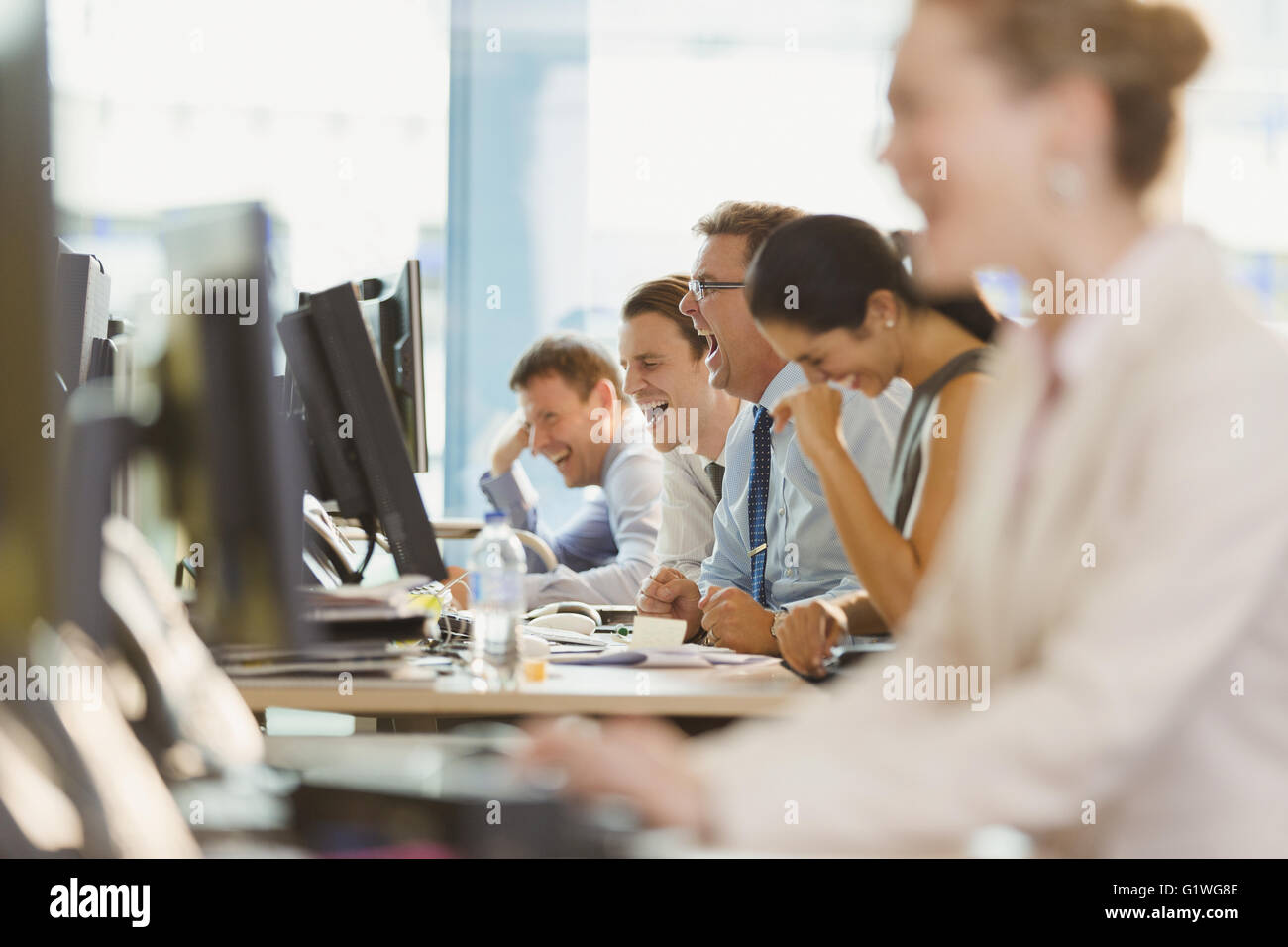 La gente di affari di ridere a scrivania in ufficio Foto Stock