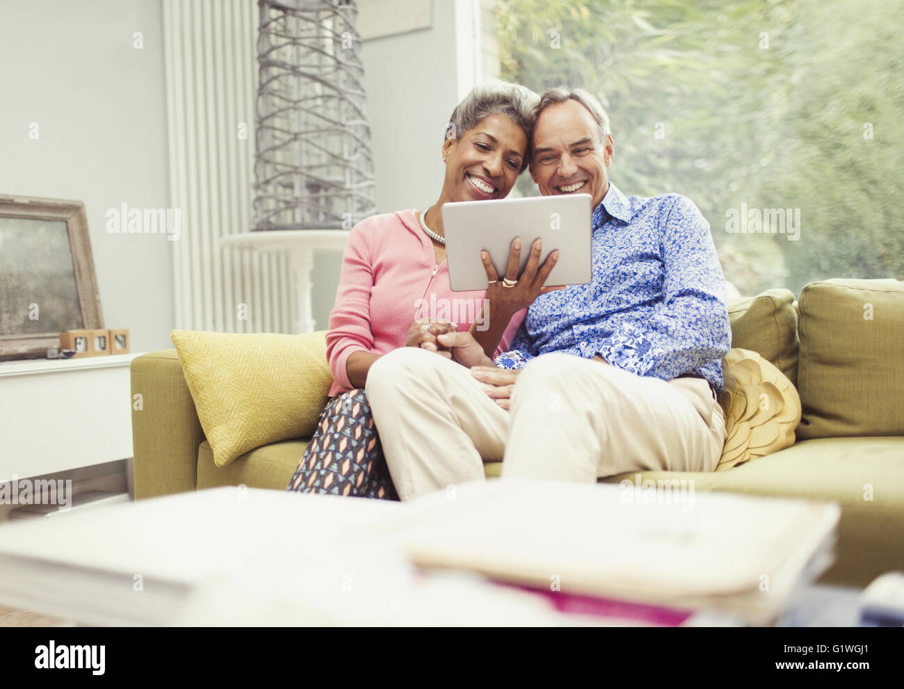 Sorridente Coppia matura con tavoletta digitale sul divano Foto Stock