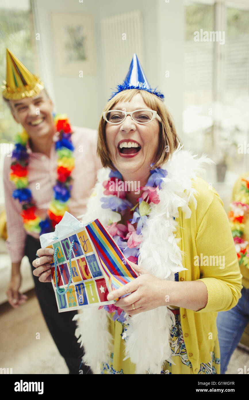 Ritratto di ridere donna matura in party hat holding regalo di compleanno Foto Stock