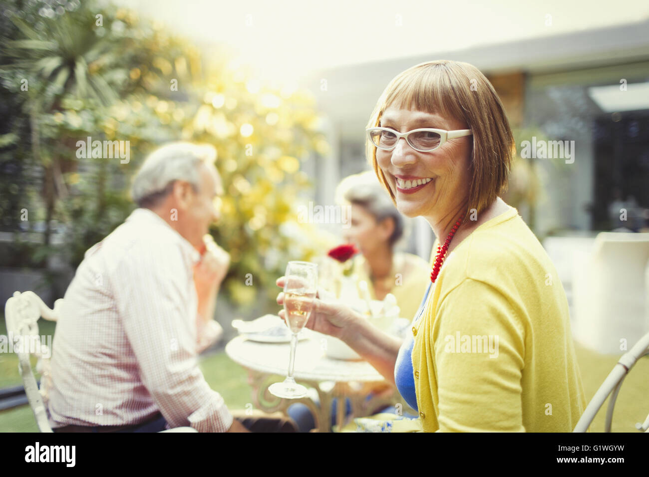 Ritratto di donna sorridente bevendo champagne al party in giardino Foto Stock