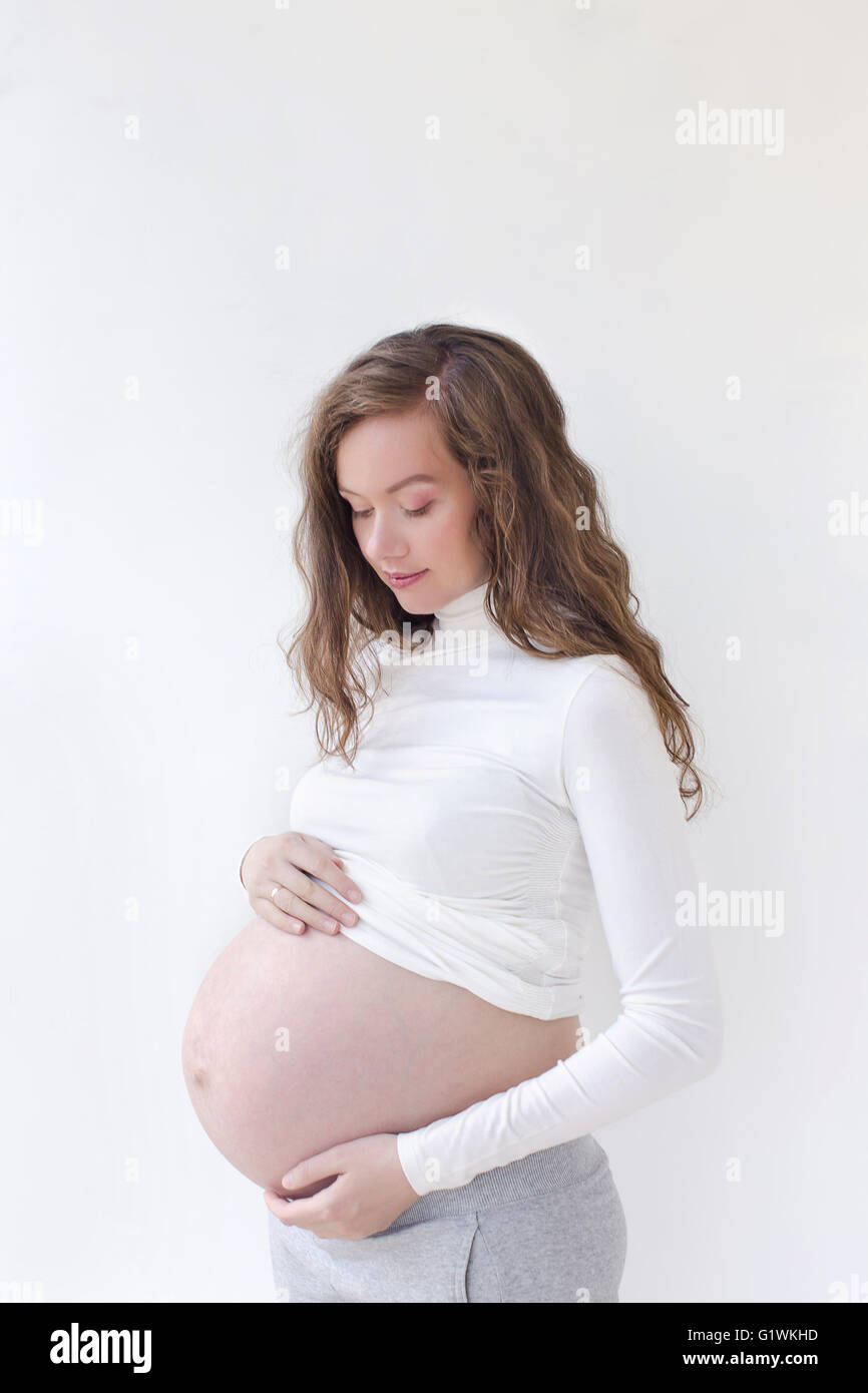 Donna incinta ad accarezzarle il ventre su bianco Foto Stock