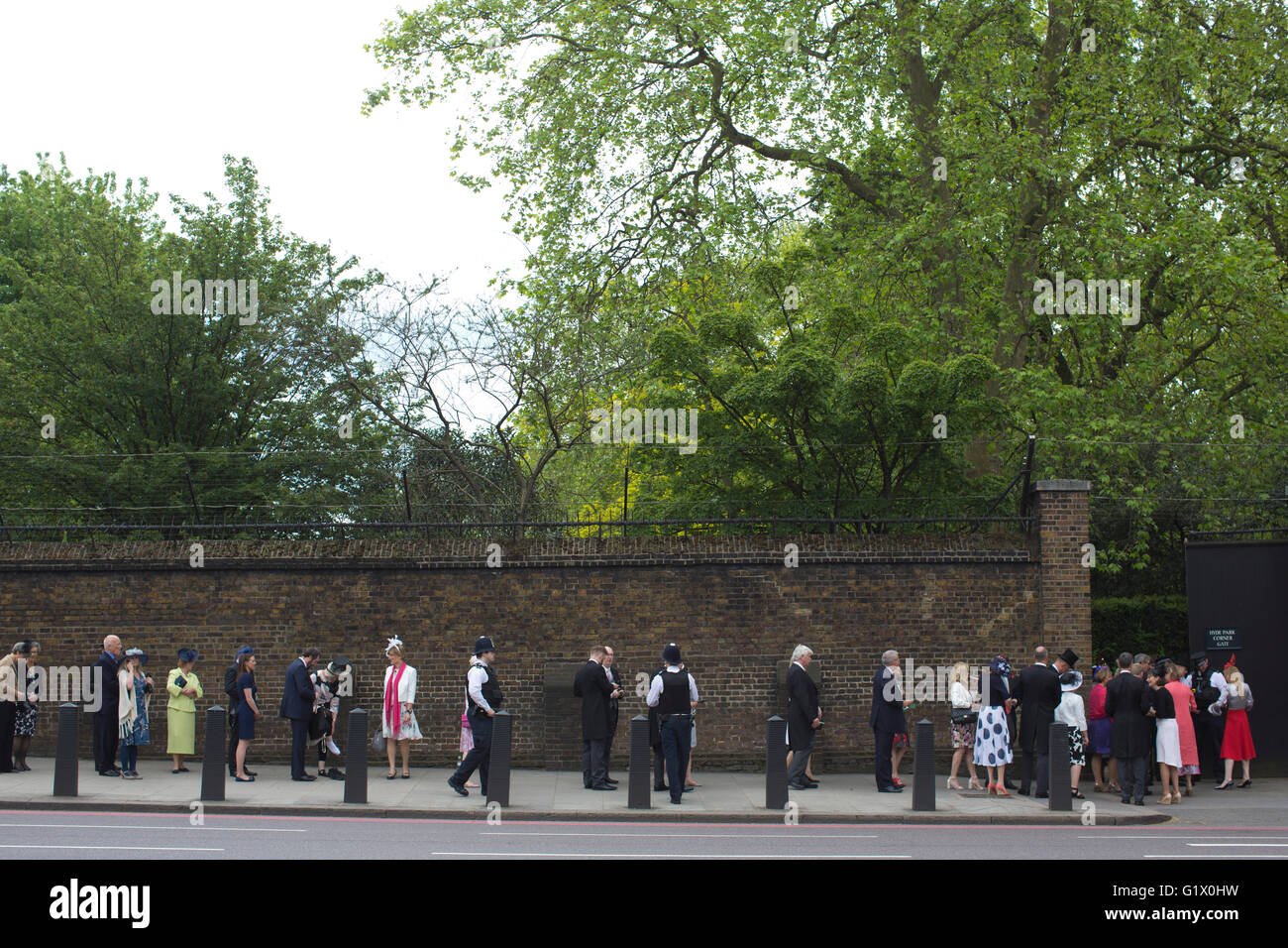 I partecipanti alla annuale della Famiglia Reale Giardino Partito coda fuori l'ingresso al Palazzo di Buckingham, central London, Regno Unito Foto Stock