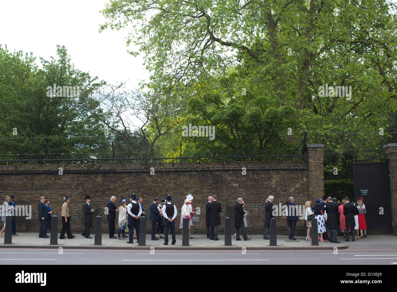 I partecipanti alla annuale della Famiglia Reale Giardino Partito coda fuori l'ingresso al Palazzo di Buckingham, central London, Regno Unito Foto Stock