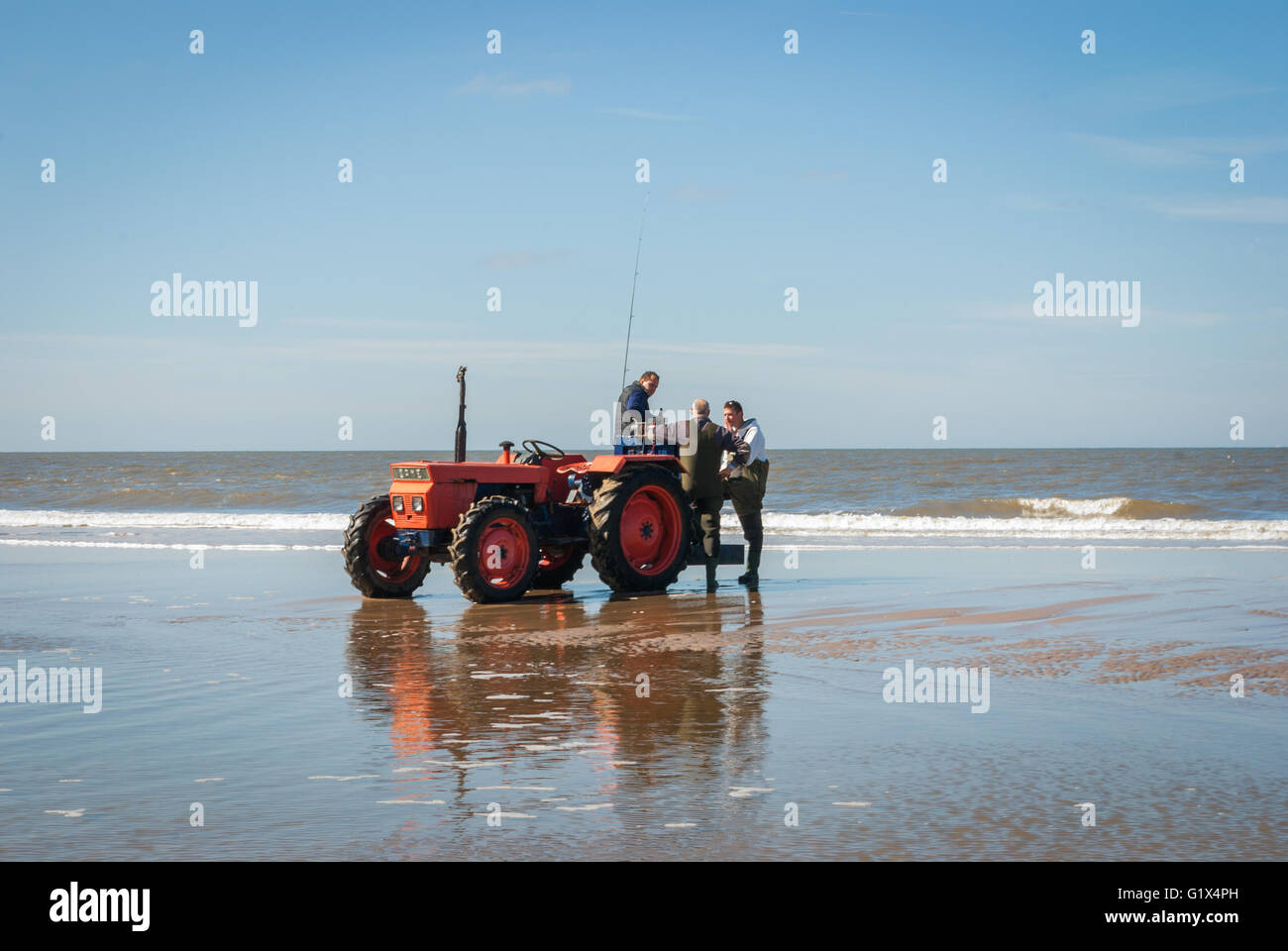 Trattore rosso e chiacchierando equipaggio in riva alla spiaggia del Mare del Nord a Egmond-aan-Zee, durante la linea di competion di pesca Foto Stock