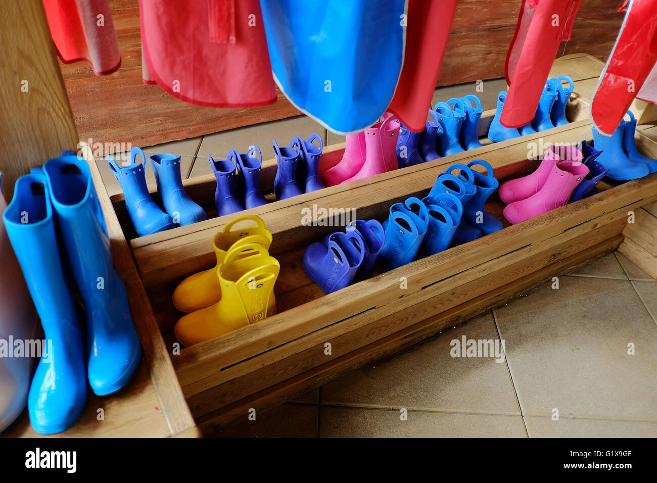 Stivali di gomma di grandi e piccole e memorizzati in un avvio in legno rack. Foto Stock