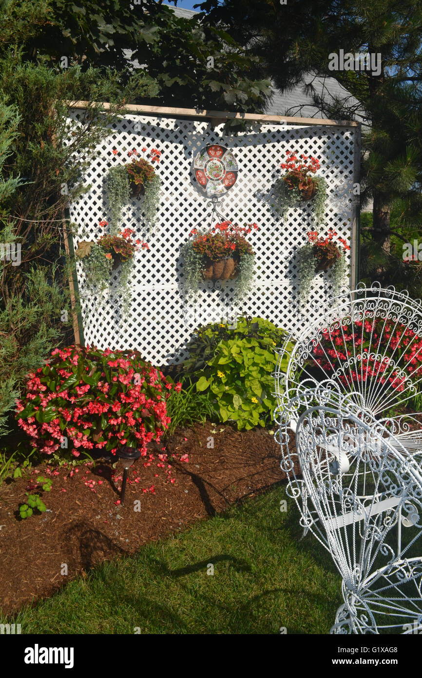 Una bellissima sistemazione floreale nel cortile con un filo bianco sedia. Foto Stock