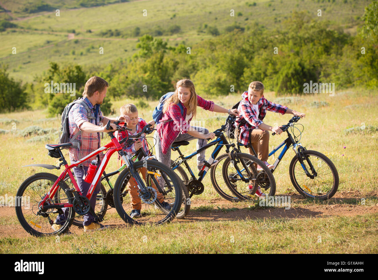 Una famiglia di quattro persone a cavallo di biciclette in montagna Foto Stock
