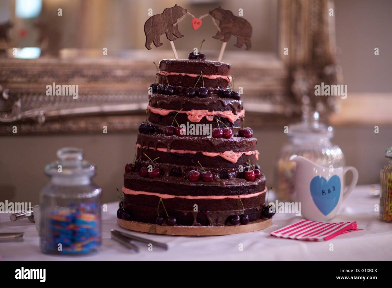 Il cioccolato torta adornata con ciliegie pronti per il taglio da parte la sposa e lo sposo. Foto Stock