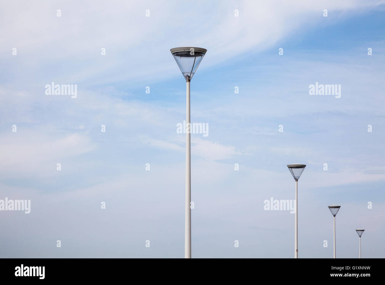 Un'immagine minimalista di quattro moderni standard di lampade al Palacio de Congresos Kursaal a San Sebastian, Spagna contro un cielo blu con nuvole luguide Foto Stock