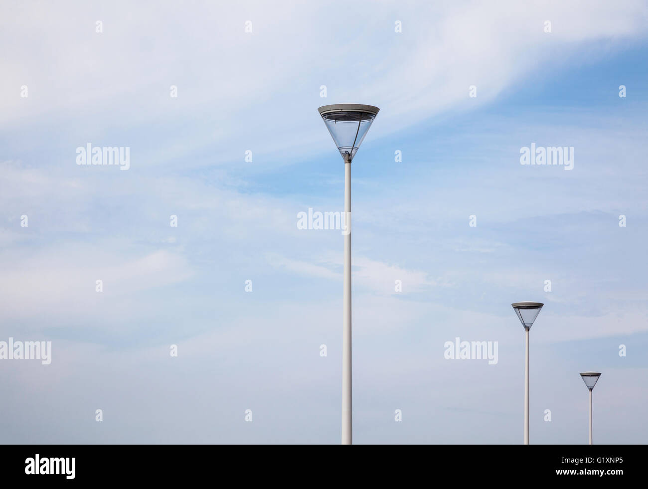 Un'immagine minimalista di tre moderni standard di lampade al Palacio de Congresos Kursaal a San Sebastian, Spagna contro un cielo blu con nuvole luguide Foto Stock