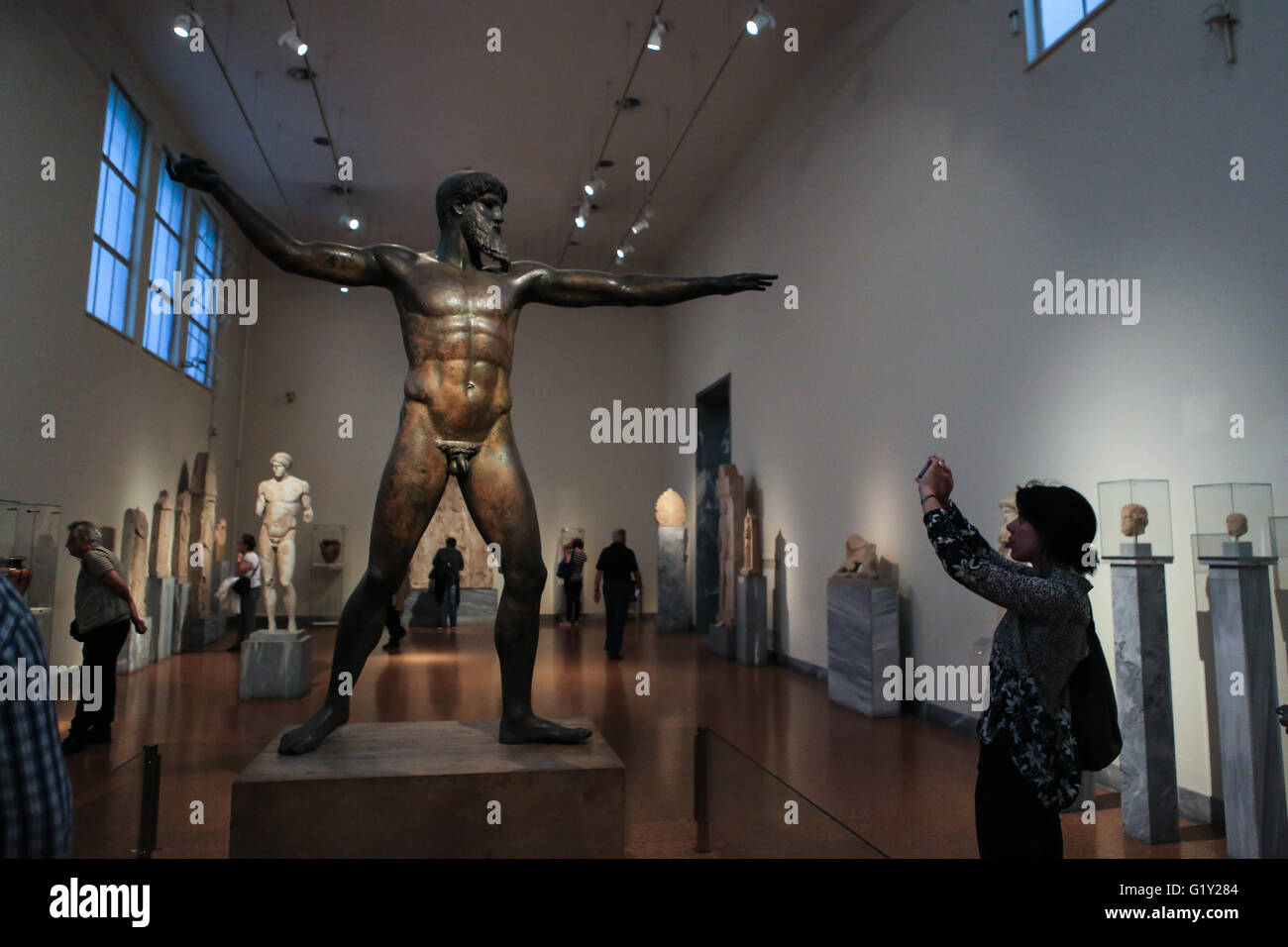 Atene. 18 Maggio, 2016. Una donna prende le immagini di una statua in bronzo di Zeus datato intorno al 460 a.c. presso il Museo Nazionale Archeologico di Atene in Grecia il 18 maggio 2016. Tra i numerosi reperti di antichità greca, nell altare sala principale del Museo Archeologico Nazionale di Atene, i visitatori hanno avuto la possibilità di viaggiare indietro nel tempo attraverso la lettura teatrale dell'Odissea di Omero, uno dei più poemi epici della Grecia antica, in occasione della Giornata Internazionale dei Musei di mercoledì. © Lefteris Partsalis/Xinhua/Alamy Live News Foto Stock