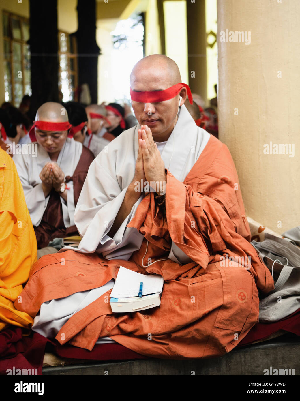 Un monaco prega durante un tibetano Chenrezig iniziazione da Sua Santità il Dalai Lama al tempio Tsuglagkhang, in McLeod Ganj, India. Foto Stock