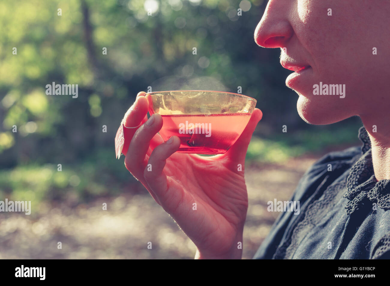 Una donna è bere il tè al di fuori in una giornata di sole Foto Stock