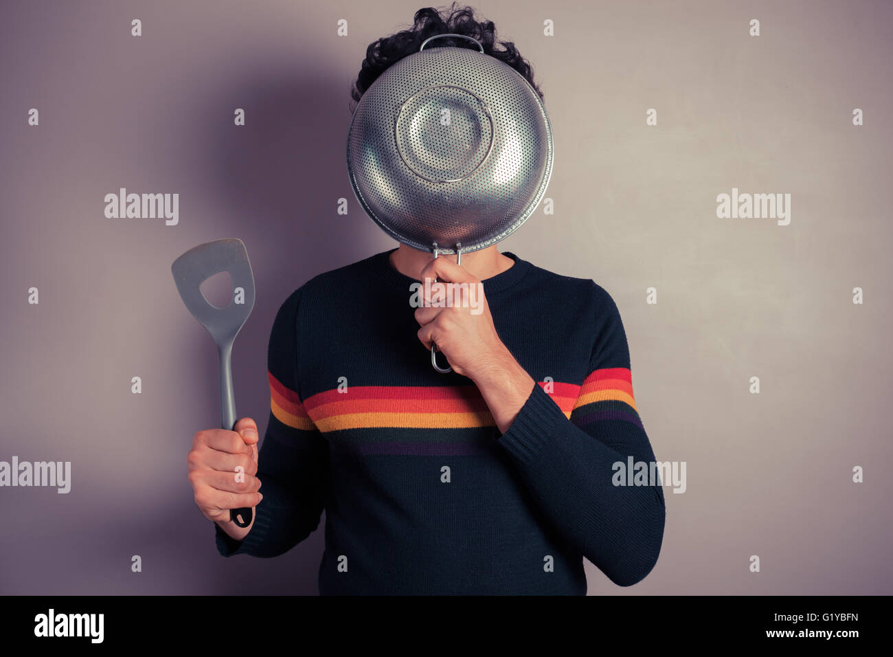 Un giovane uomo si nasconde il suo volto dietro uno scolapasta Foto Stock