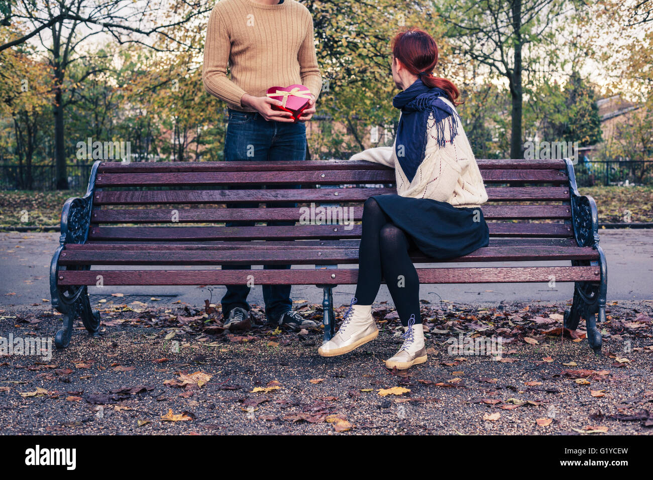 Un giovane uomo è l'incontro con una donna nel parco ed è dare a lei un bellissimo regalo Foto Stock