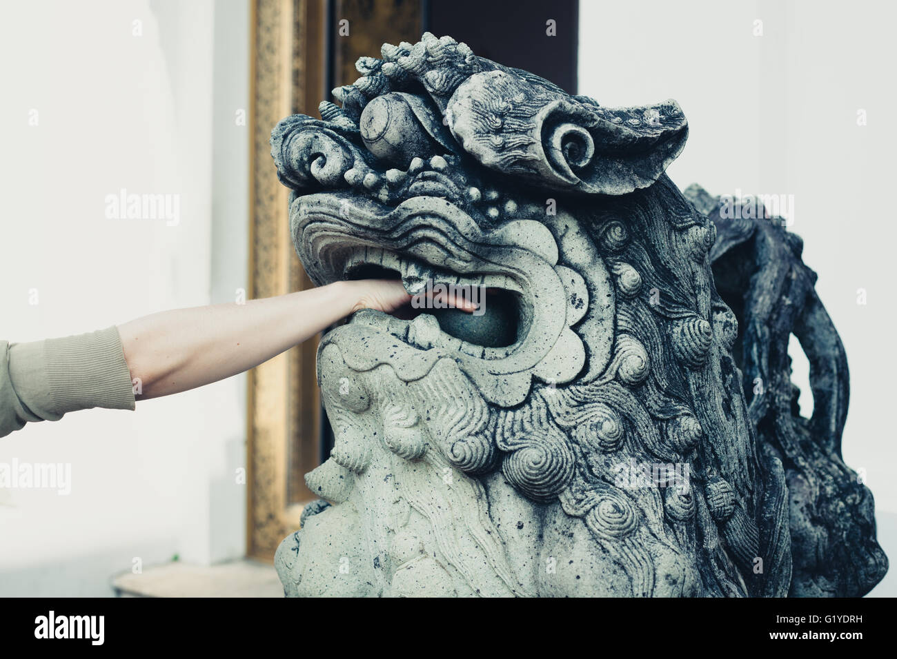Una giovane donna è giocare con le sfere nella bocca di un leone cinese statua Foto Stock
