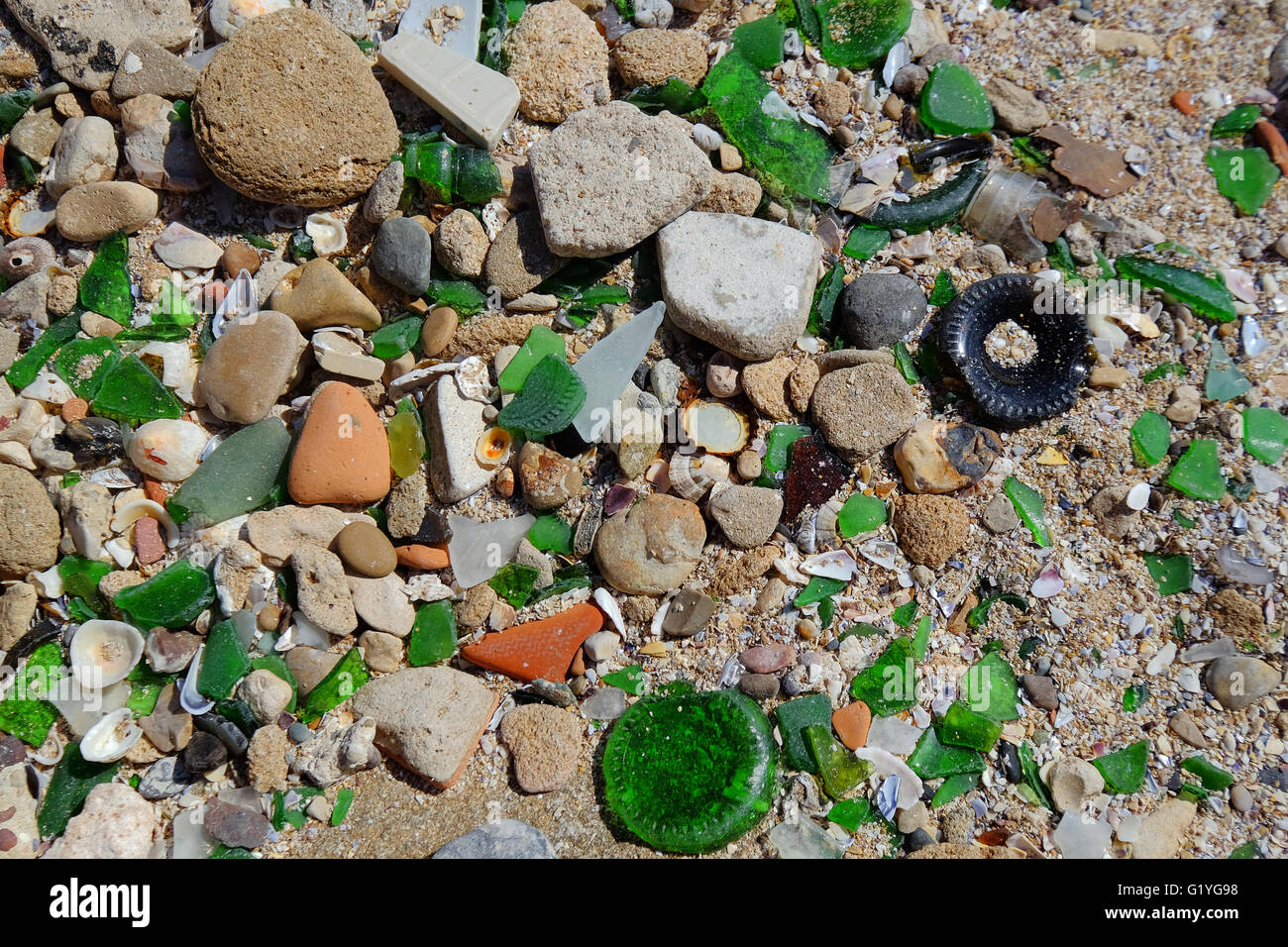 Grandi quantità di vetro rotto tra i granelli di una spiaggia sulla costa del Marocco Foto Stock