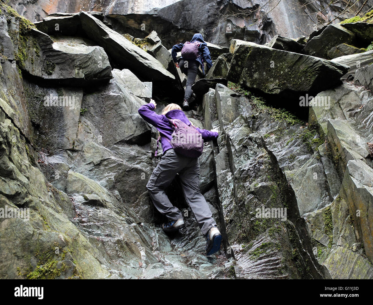 Due bambini di rocce di arrampicata in una cava della Cattedrale, Cumbria Foto Stock