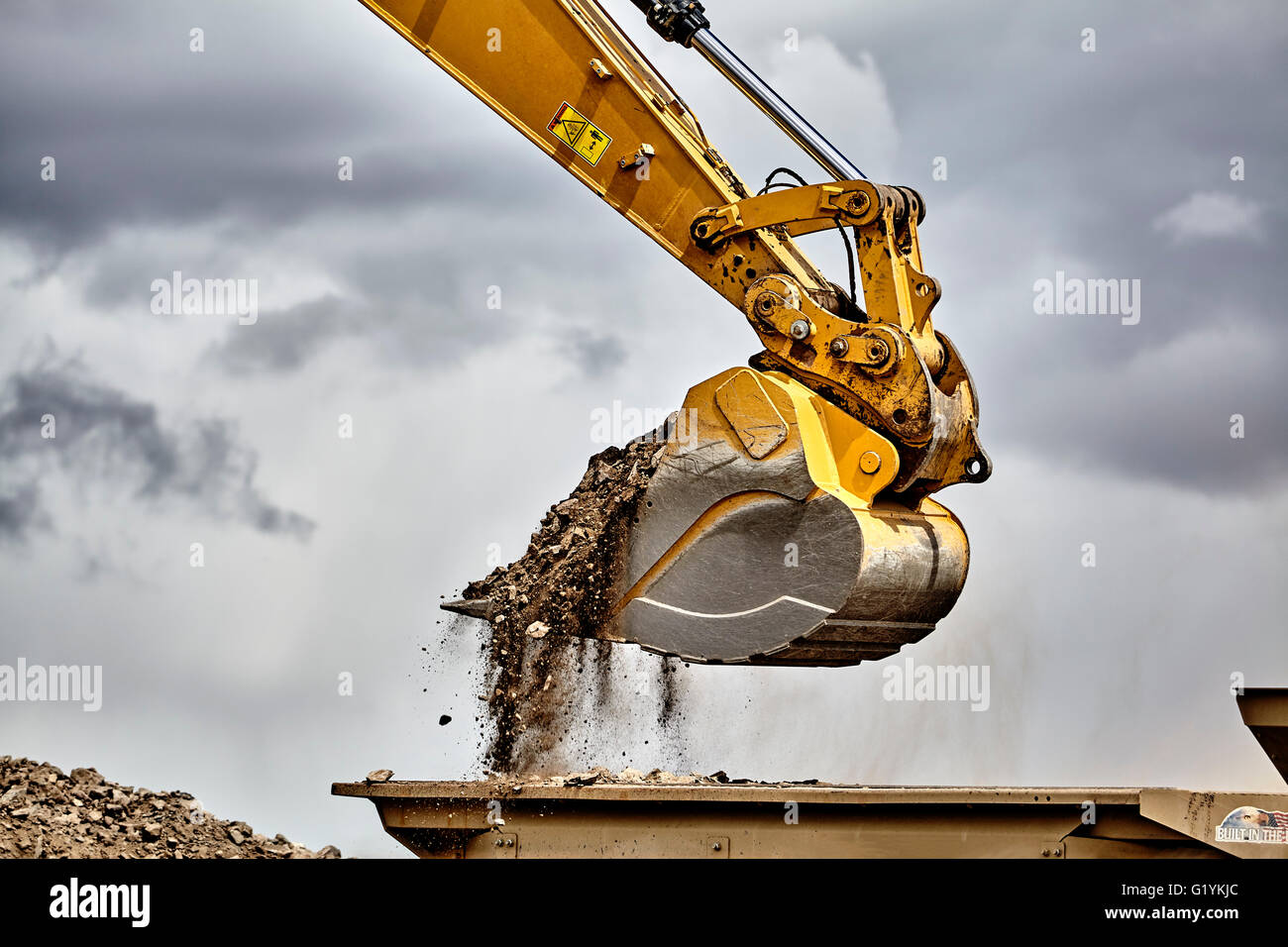 Industria di costruzione di apparecchiature pesanti escavatore ghiaia di movimentazione in cantiere cava con cielo tempestoso Foto Stock