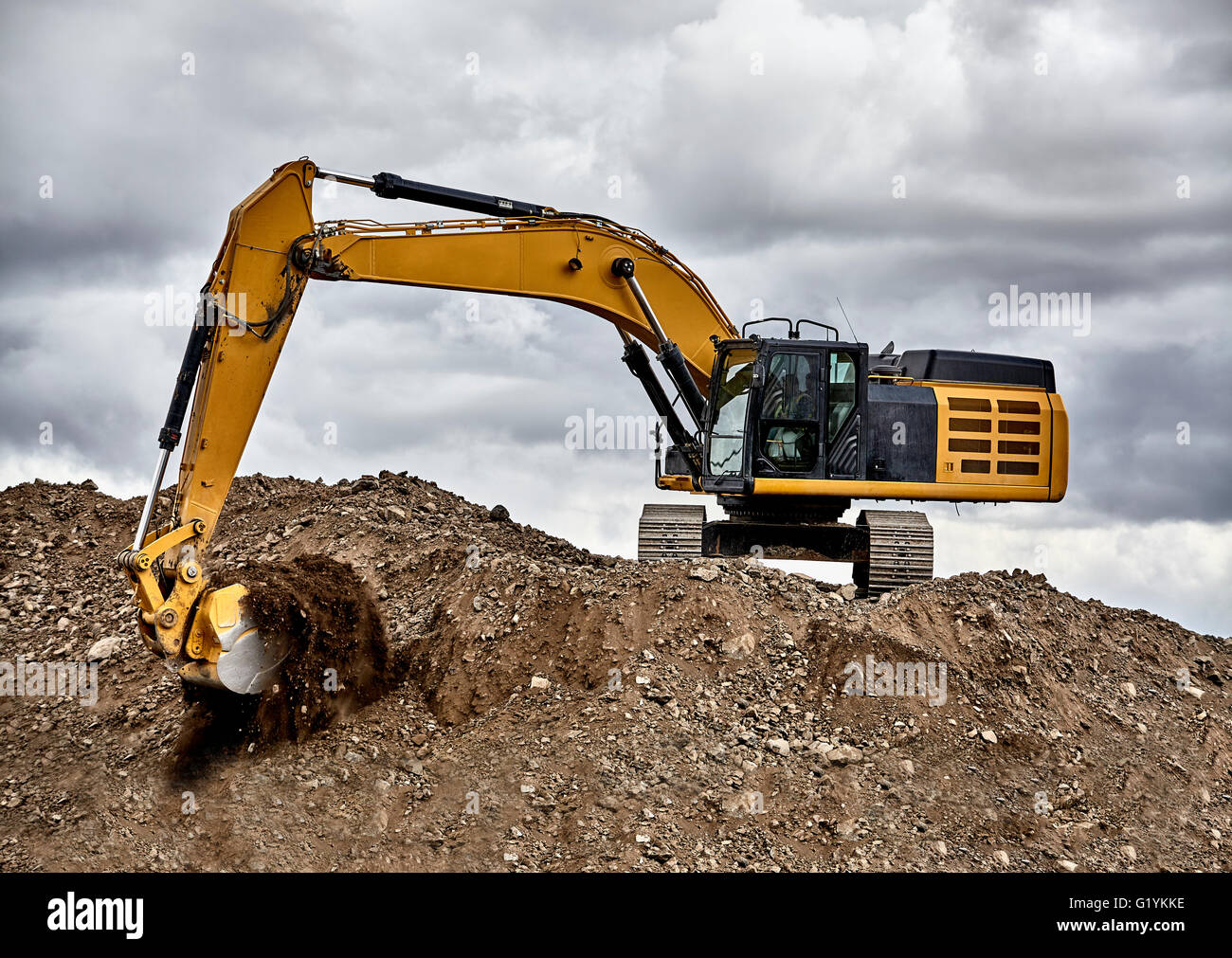 Industria di costruzione di apparecchiature pesanti escavatore ghiaia di movimentazione in cantiere cava con cielo tempestoso Foto Stock
