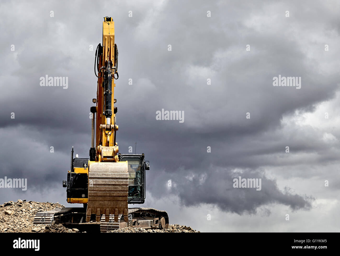 Industria di costruzione di apparecchiature pesanti escavatore ghiaia di movimentazione in cantiere cava con cielo tempestoso Foto Stock