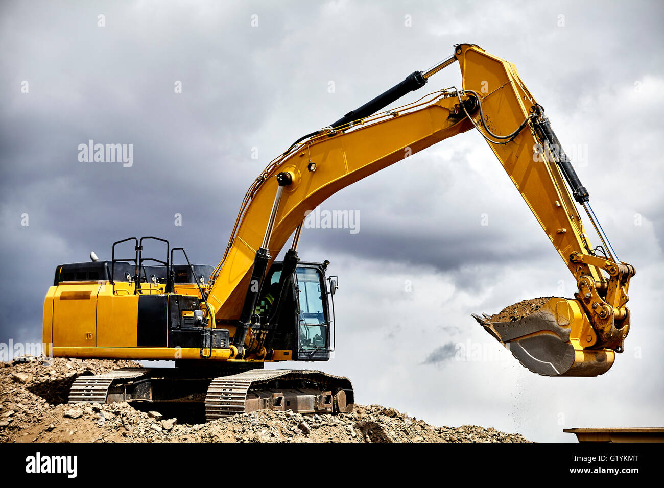 Industria di costruzione di apparecchiature pesanti escavatore ghiaia di movimentazione in cantiere cava con cielo tempestoso Foto Stock