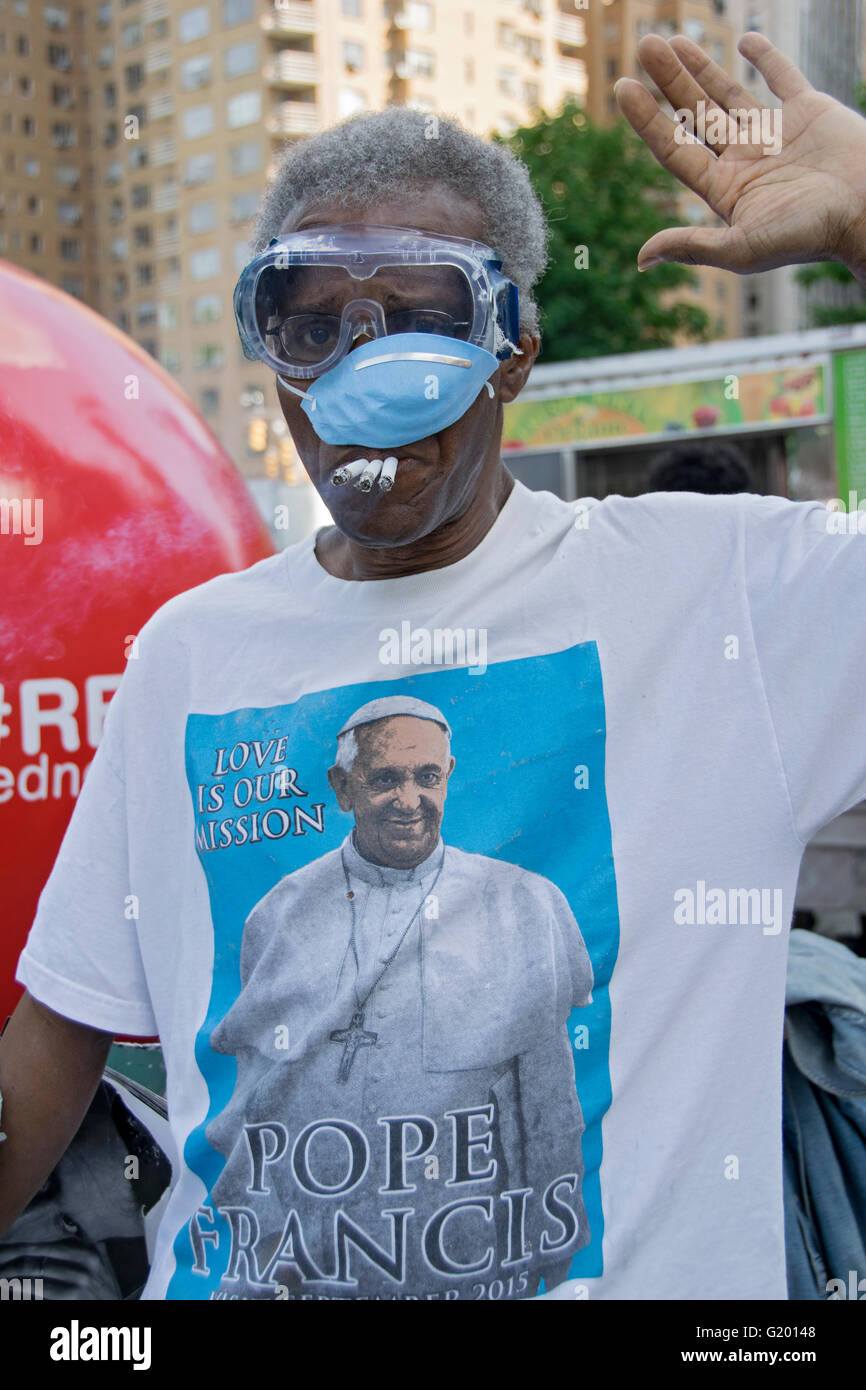 Un eccentrico newyorkese di fumare tre sigarette, indossa una maschera facciale e di un papa Francesco t shirt vicino a Columbus Circle in NYC. Foto Stock