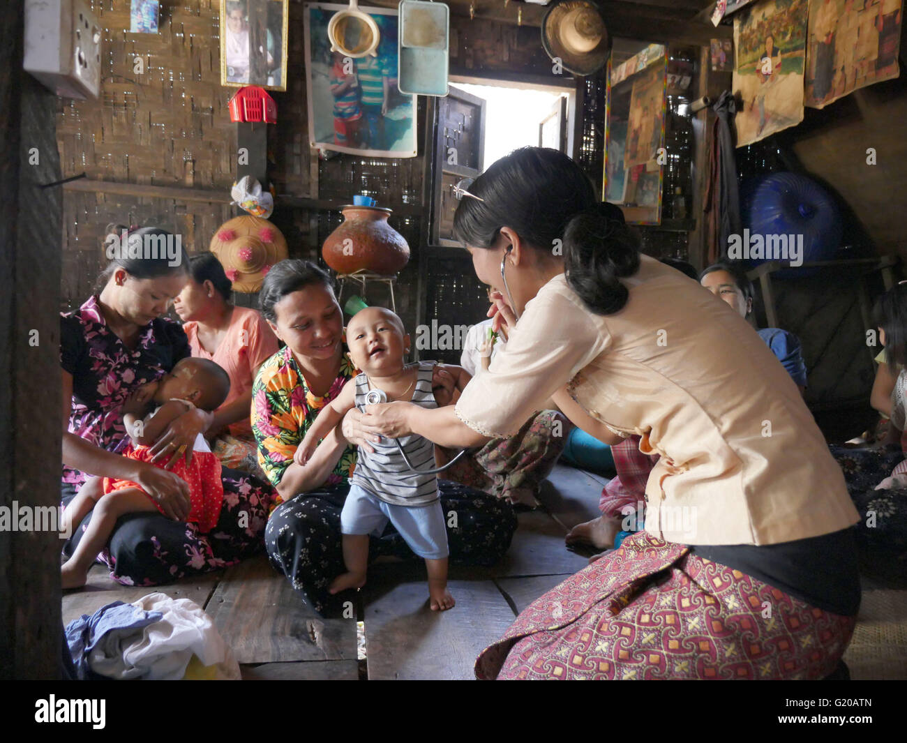 MYANMAR Hlaing Thayer, una delle baraccopoli della capitale Yangon dove le persone sono stati riposizionati dopo il 2008 Typhoon. MCHAN è attiva in questo settore con la sua comunità basata programma sanitario. Visitare una casa dove MCHAN esegue health check-up e conduce il workshop. MCHAN infermiera Monica Myu imbardata Hli esamina un bambino sano. Foto Stock