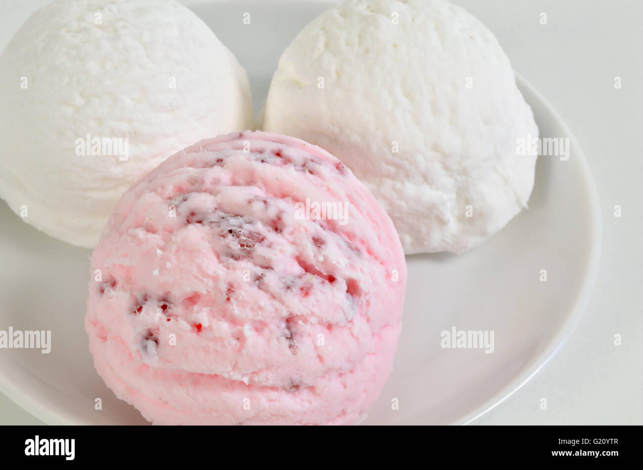 Tre convogliatori del bianco e del rosa gelati su piastra bianca, close up, full frame, orizzontale Foto Stock