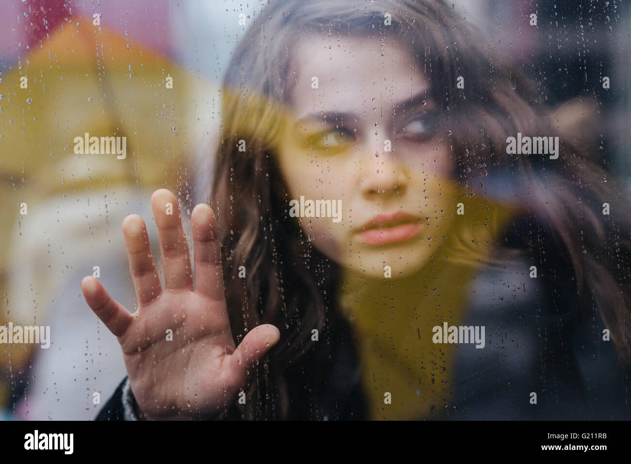 Giovane donna guardando attraverso la finestra in un giorno di pioggia Foto Stock