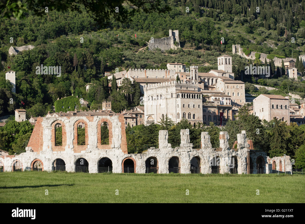 Gubbio in Umbria. In primo piano, l'antico teatro romano. Sullo sfondo lo skyline della città medievale. Foto Stock