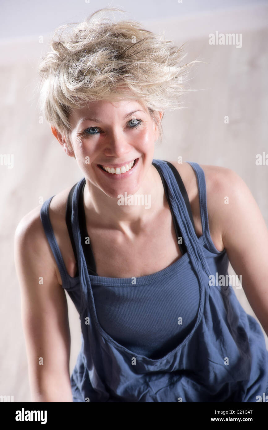 Ritratto di atletica unico bella donna bionda in abito blu ridendo e guardando in avanti sopra la pietra Sfondo marmo Foto Stock