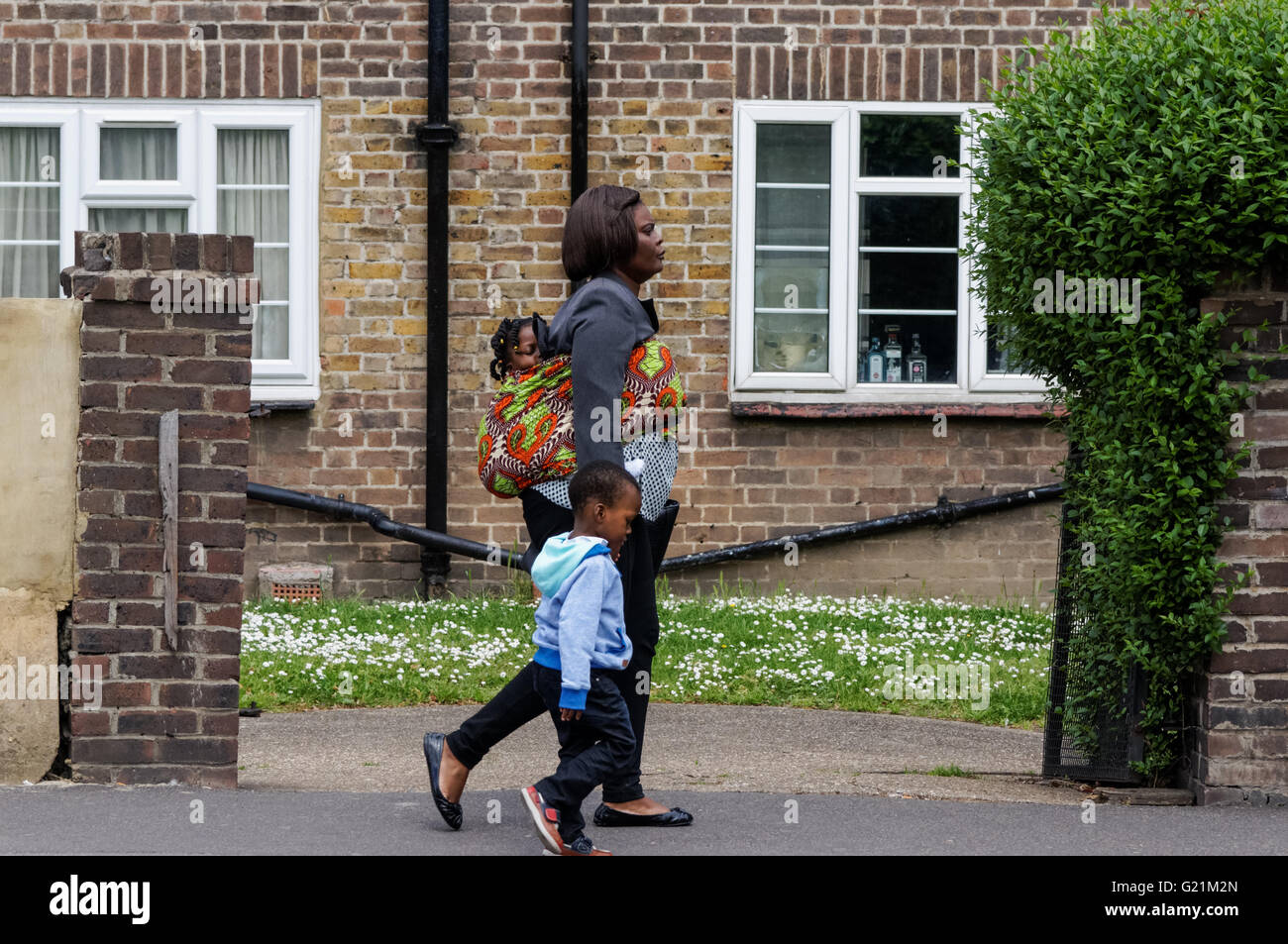 Madre di due figli a piedi attraverso consiglio estate in London, England Regno Unito Regno Unito Foto Stock