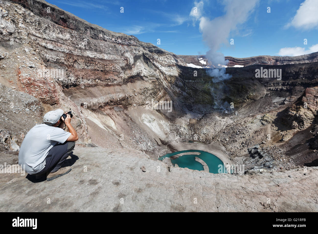 Tourist nel cratere attivo del vulcano Gorely shoot del vulcano deliberando fumarola e il cratere del lago. La Russia, Estremo Oriente, Kamchatka Foto Stock
