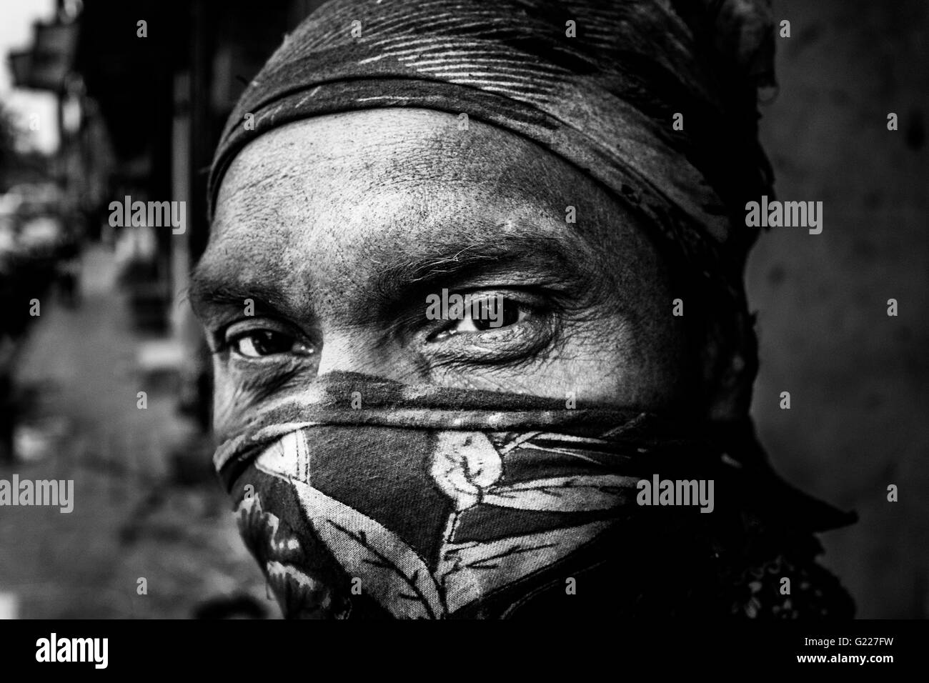 Uomo che indossa una sciarpa davanti alla bocca con una faccia sporca, Delhi, India Foto Stock