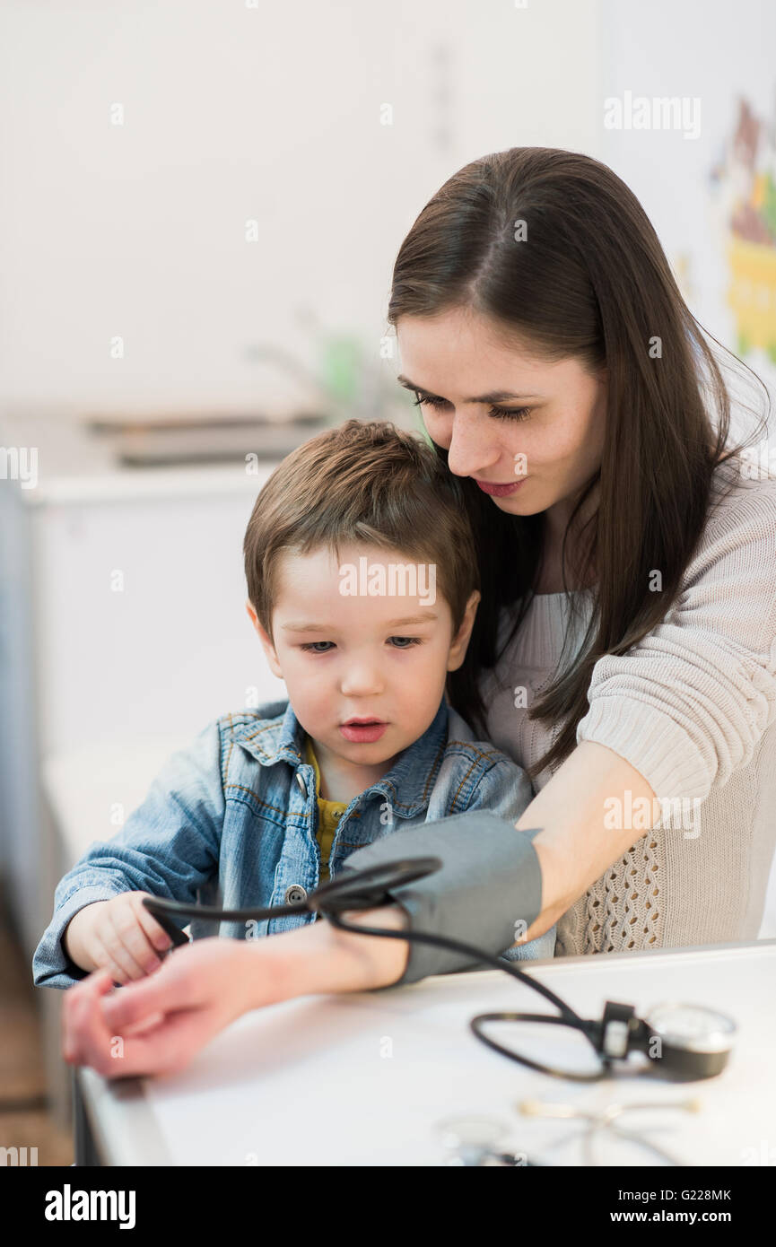 Donna attraente e il suo bambino con un apparecchio per la misurazione della pressione sanguinea tonometro Foto Stock