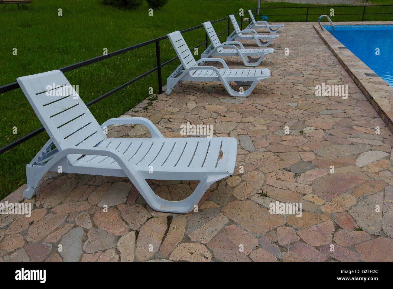 Immagine di sfocatura di sedie in plastica bianca mediante l uso della piscina per lo sfondo. Foto Stock