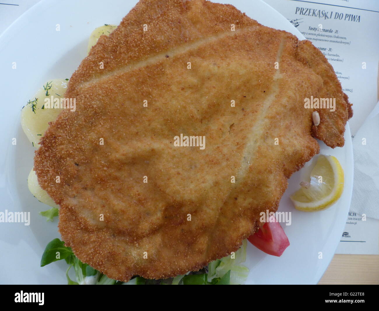 Polonia - Wroclaw. 'Schabowy', un equivalente al Wiener Schnitzel copre appena circa tutta la piastra Foto Stock