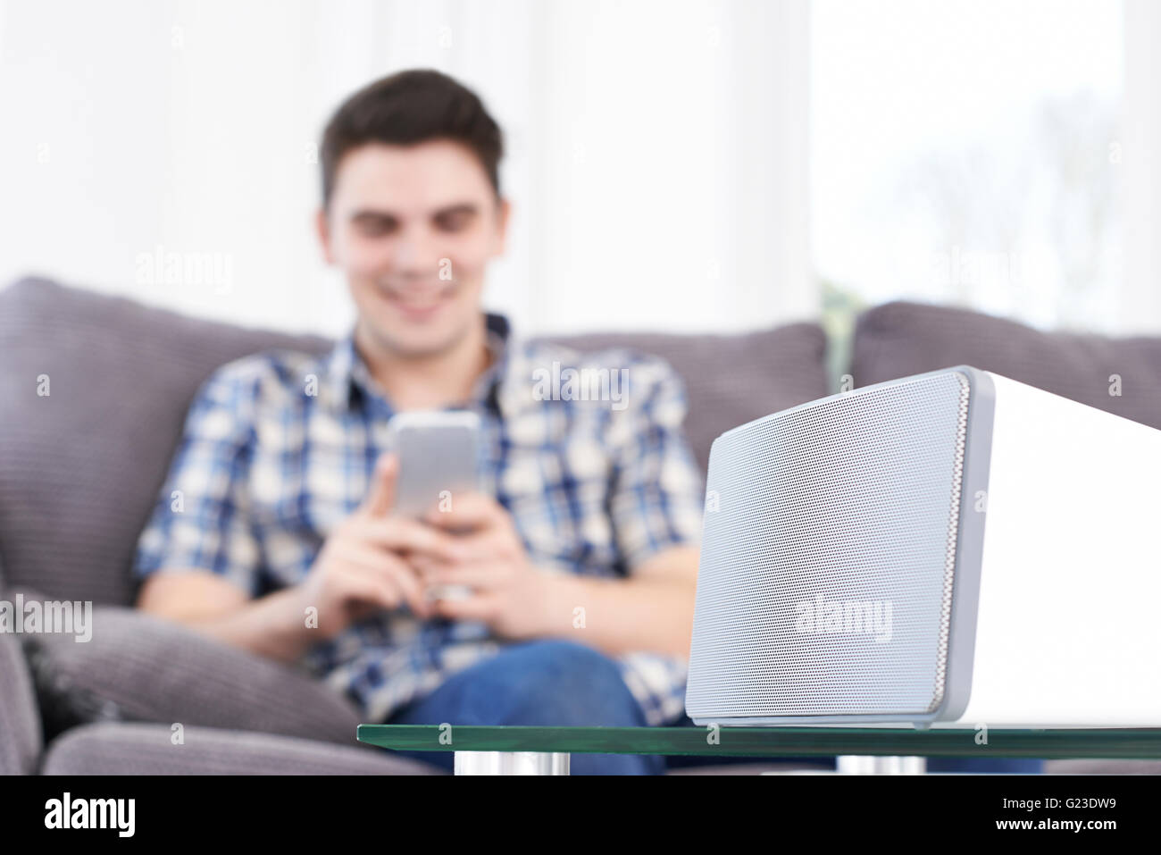 L'uomo streaming di musica dal telefono cellulare per altoparlante senza fili Foto Stock