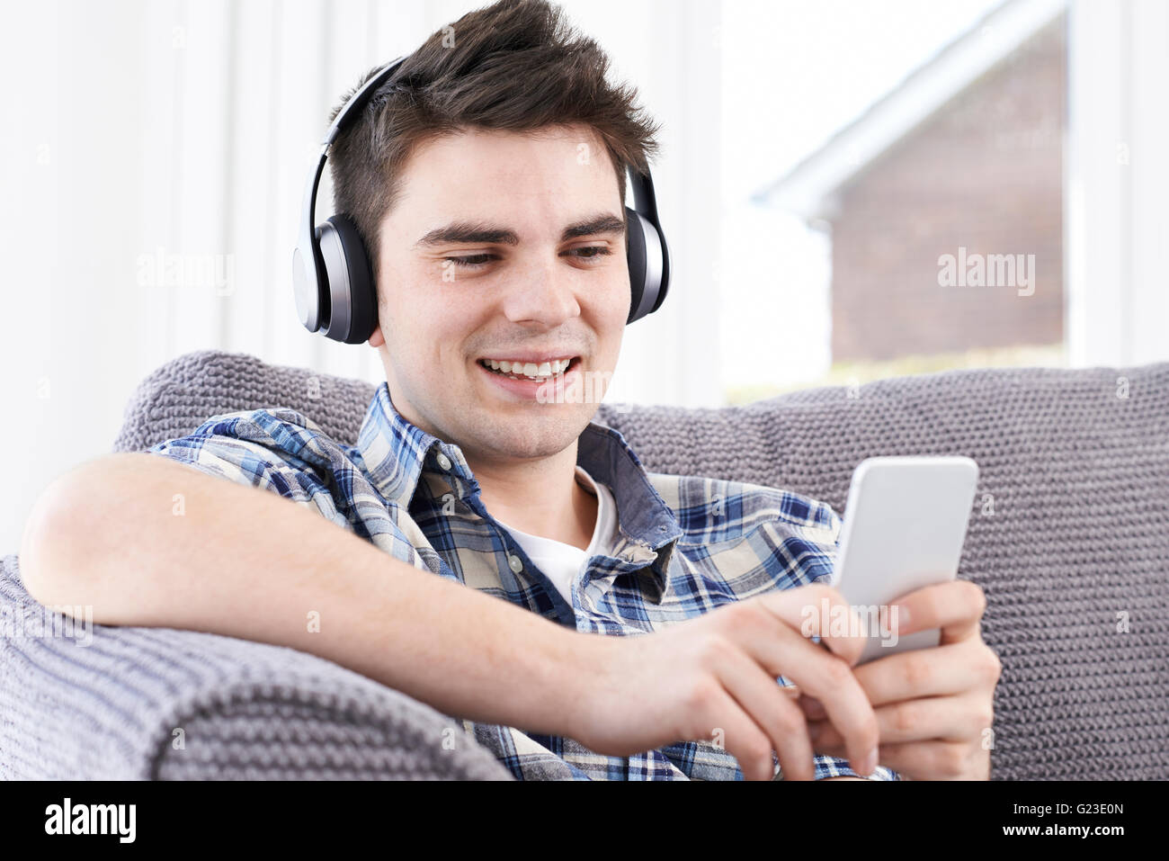 L'uomo streaming di musica dal telefono cellulare alle cuffie senza fili Foto Stock