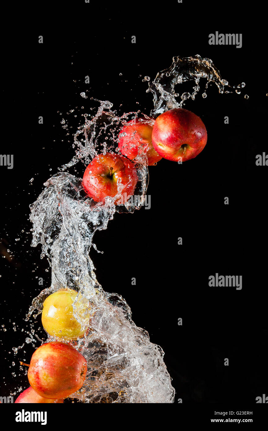 Un paio di mele rosse, volare nello spazio con l'acqua su sfondo nero Foto Stock