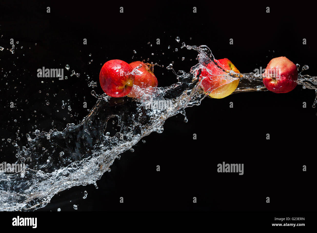 Le mele rosse, volare nello spazio con l'acqua su sfondo nero Foto Stock