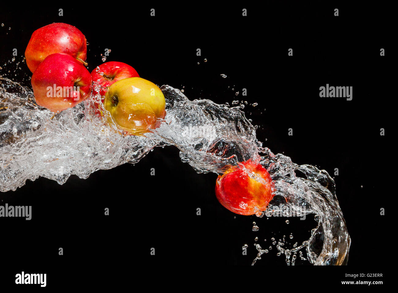 Un paio di mele rosse, volare nello spazio con l'acqua su sfondo nero Foto Stock