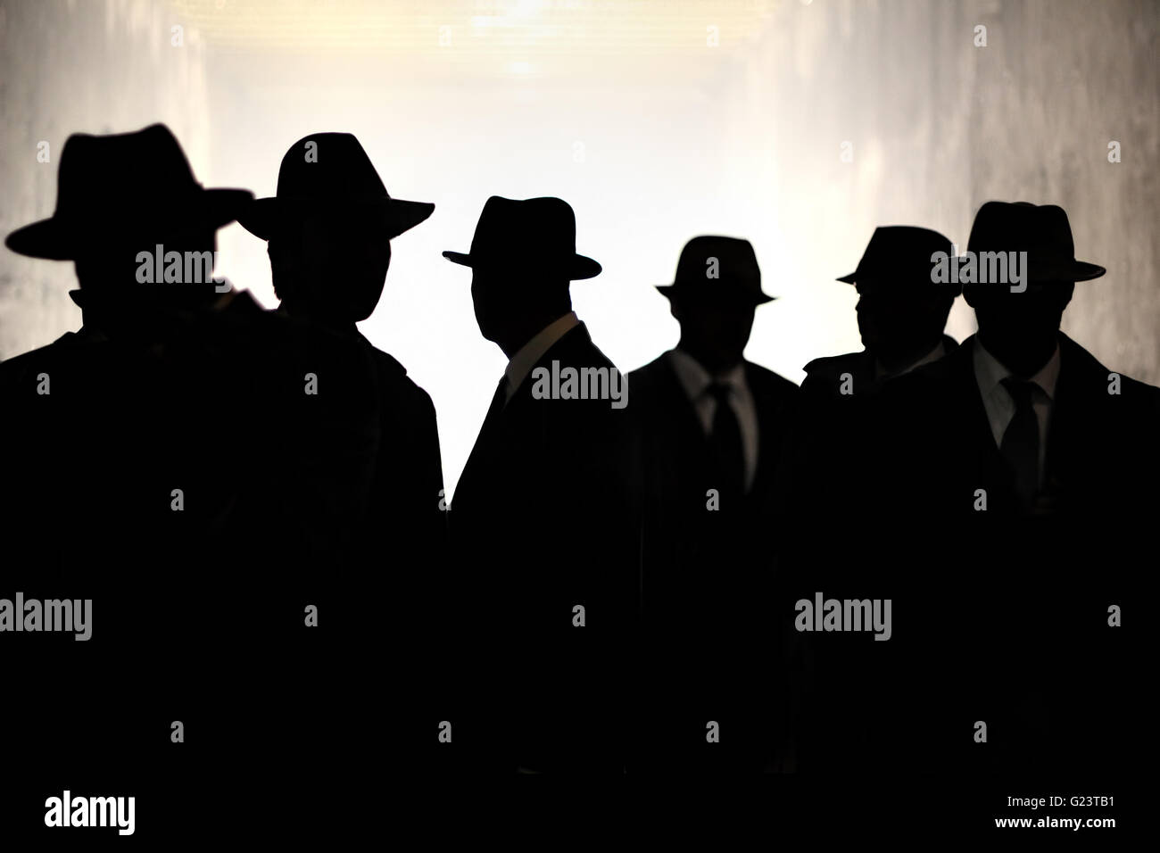 Diversi media in abiti e cappelli fedora stand in silhouette. Spy, Agente Segreto Tema. Sicurezza, privacy, concetto di sorveglianza. Foto Stock