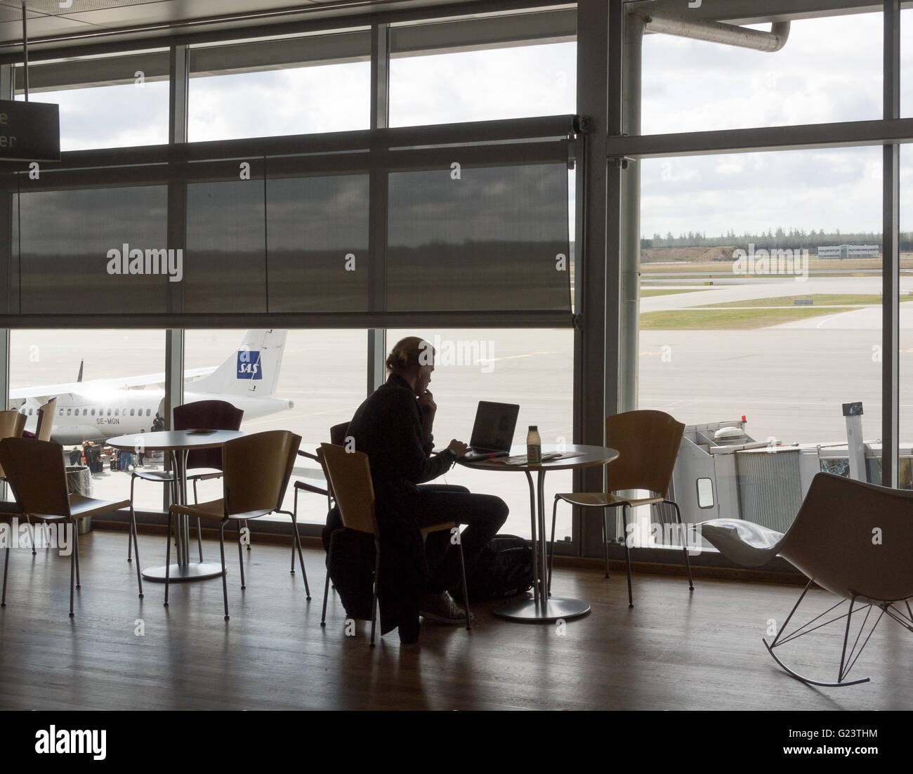 Business Traveler lavorando su un computer portatile al gate di partenza dall'aeroporto di Billund, Danimarca, area partenze. Foto Stock