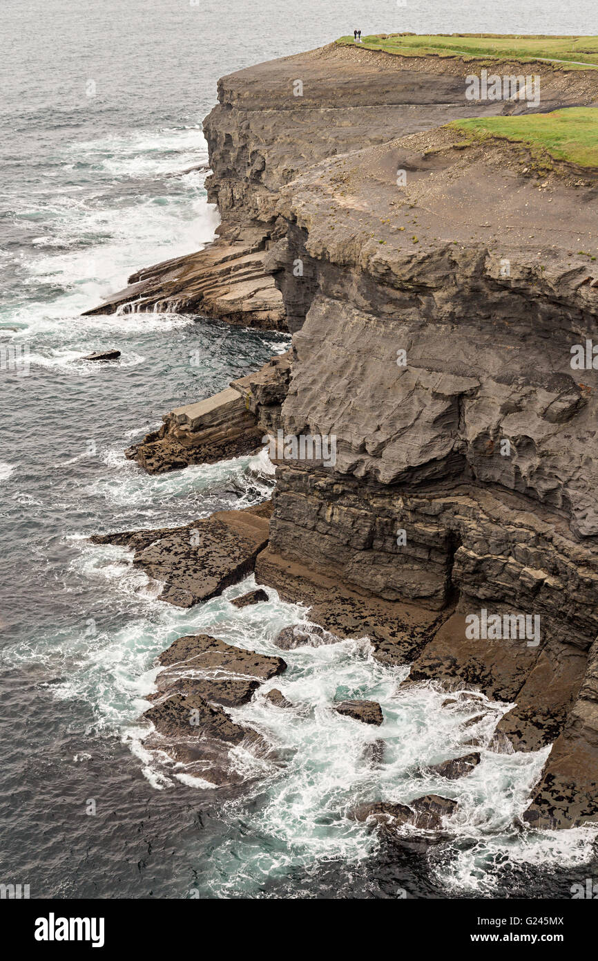 Scogliere sul mare con due persone sul promontorio sul Loop Trail Head, Co. Clare, Irlanda Foto Stock
