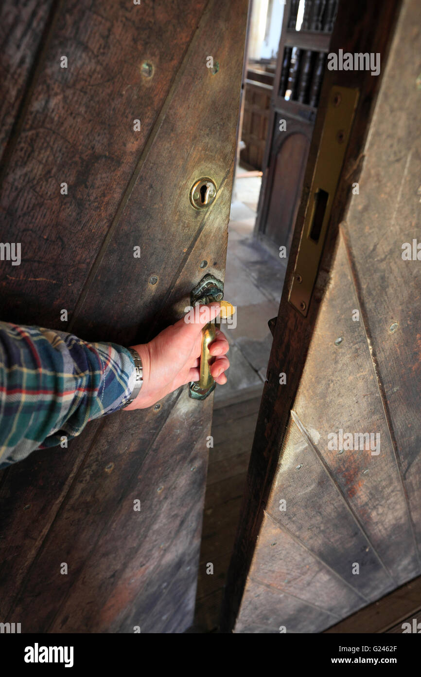 L'uomo l'apertura di una porta della chiesa, Walpole St Peter, Norfolk. Foto Stock