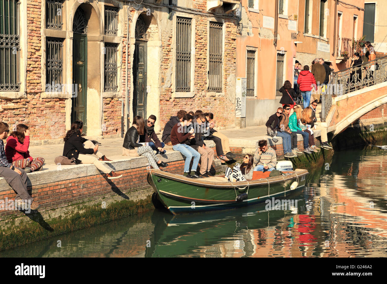 Giovani godendo una giornata di sole in un canale di Venezia in primavera Foto Stock