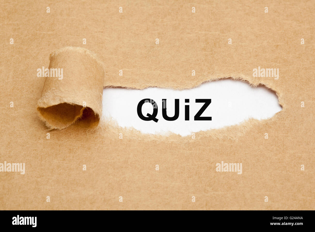 La parola Quiz che appaiono dietro strappato carta marrone. Foto Stock